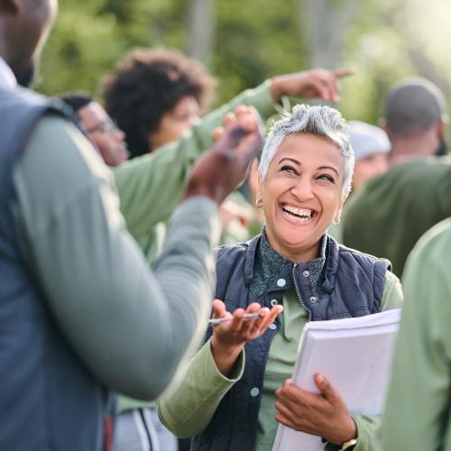 Smiling woman in casual attire engaging with a group outdoors.